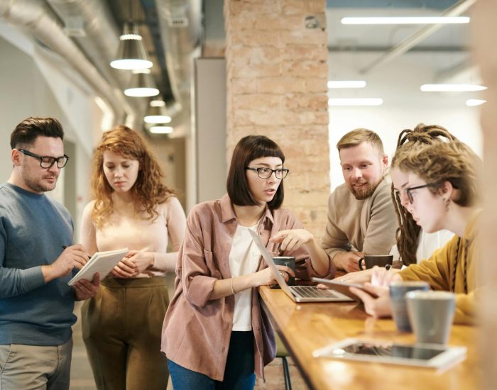 A diverse group of coworkers in a modern office engaged in teamwork using technology.