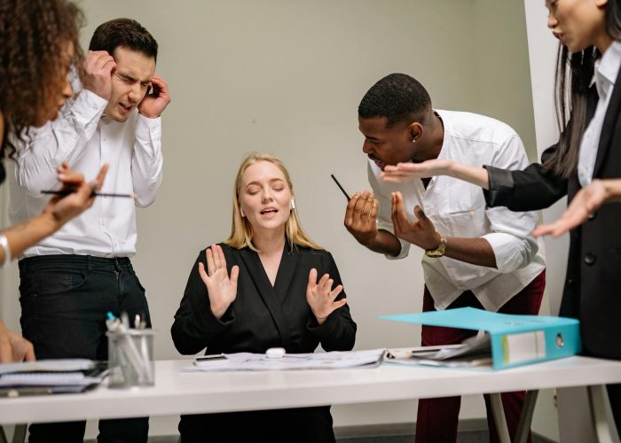 Diverse employees engaged in a heated discussion at a workplace meeting, showcasing stress and tension.